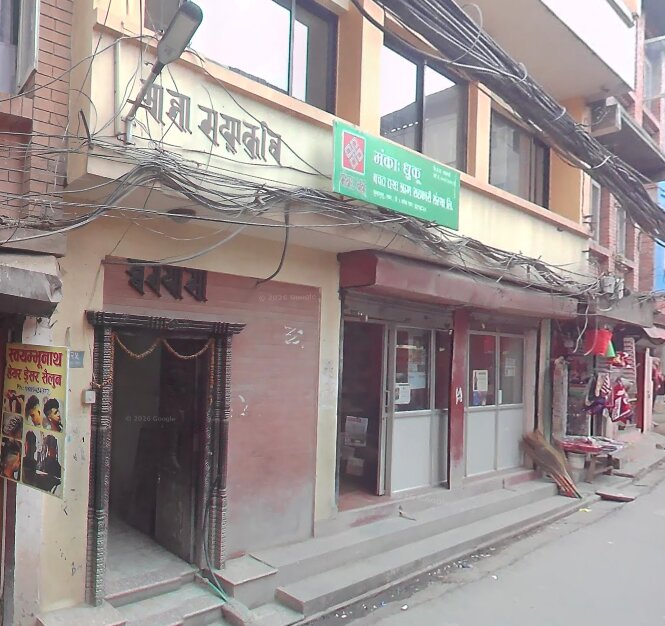 A narrow doorway with a carved wooden frame between two shops on Cittadhar Mārg, with the library's name painted high above
