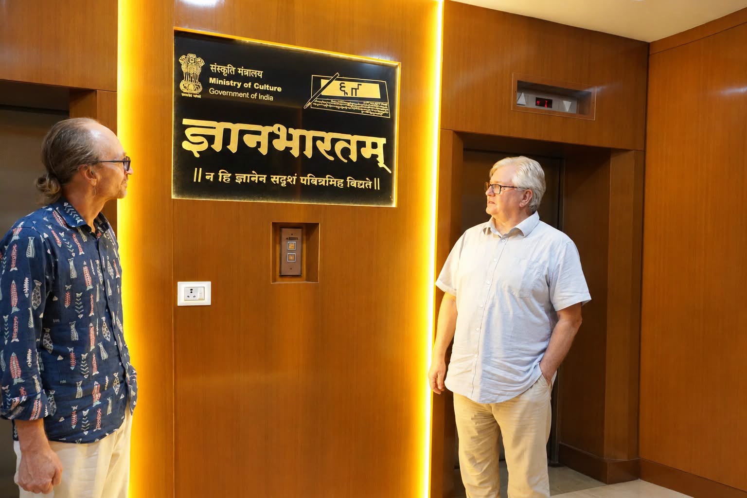 Jason Birch and Dominik Wujastyk beside the Gyan Bharatam emblem and motto