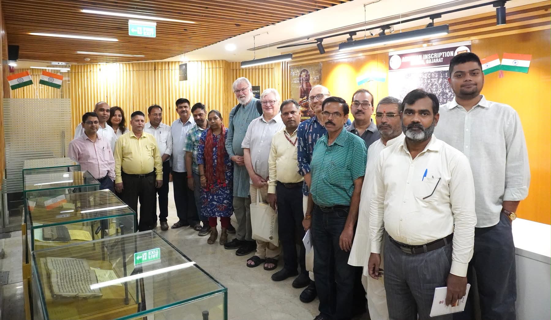Suśruta Project members with the Gyan Bharatam team beside a display of manuscripts