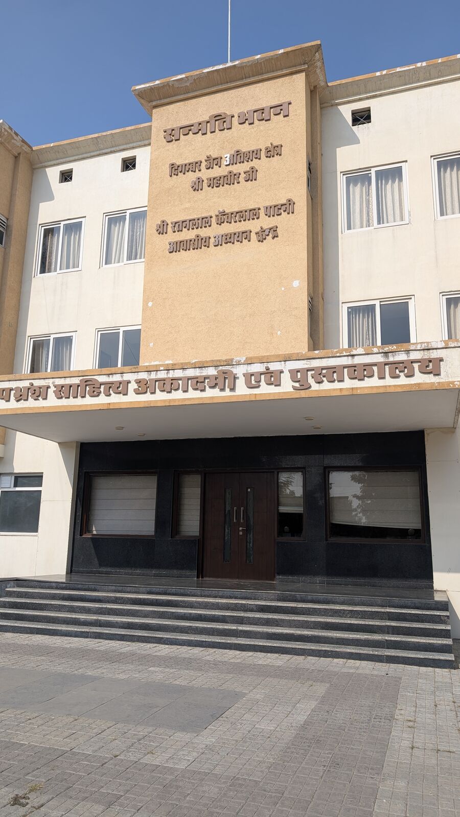The front of the Sanmati Bhavan building, with Hindi inscriptions naming the Apabhraṃśa Sāhitya Akādamī evaṃ Pustakālaya