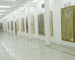 A long pillared gallery lined with large framed cloth paintings